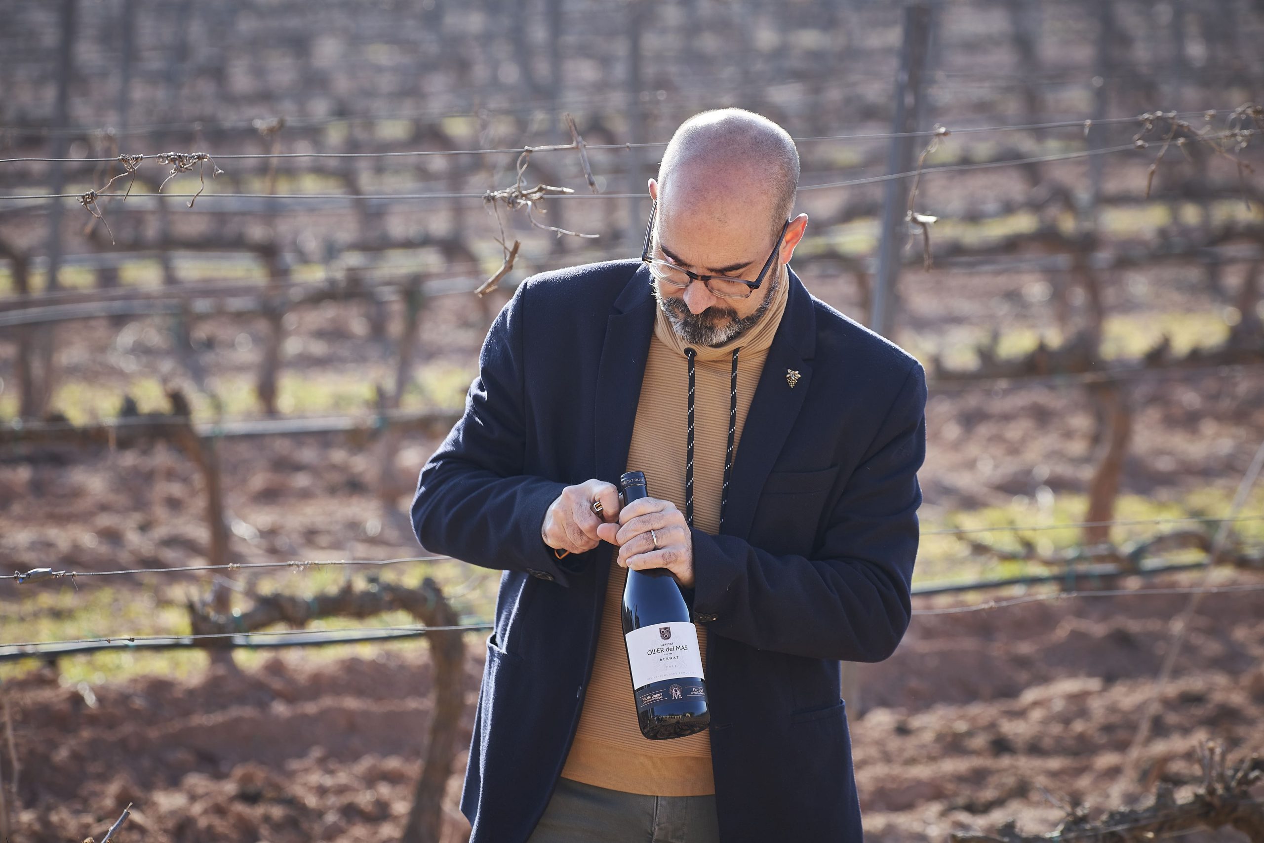Josep Pelegrín descorchando botella de vino en viñedo Oller del Mas